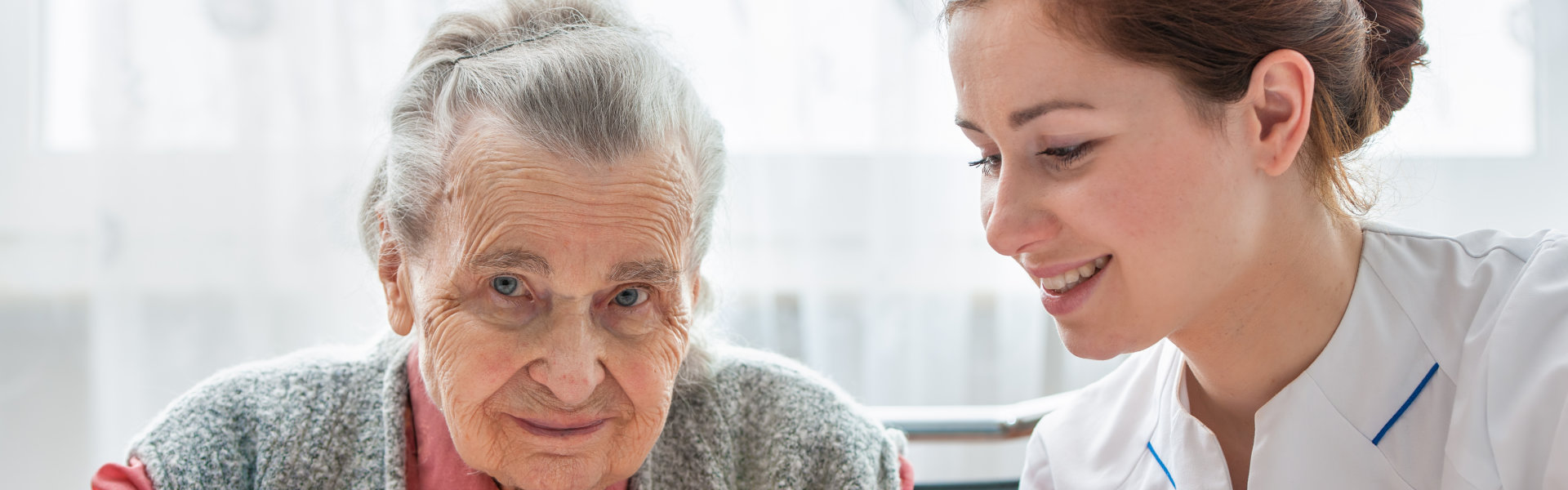 Elder care nurse playing jigsaw puzzle with senior woman in nursing home